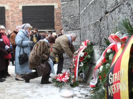 Byli więźniowie składają kwiaty przy Ścianie Śmierci na terenie byłego obozu KL Auschwitz-Birkenau